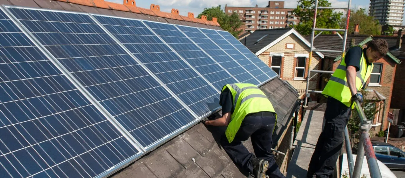 Workers install photovoltaic solar panels on the slate roof of a Victorian house in London, England.