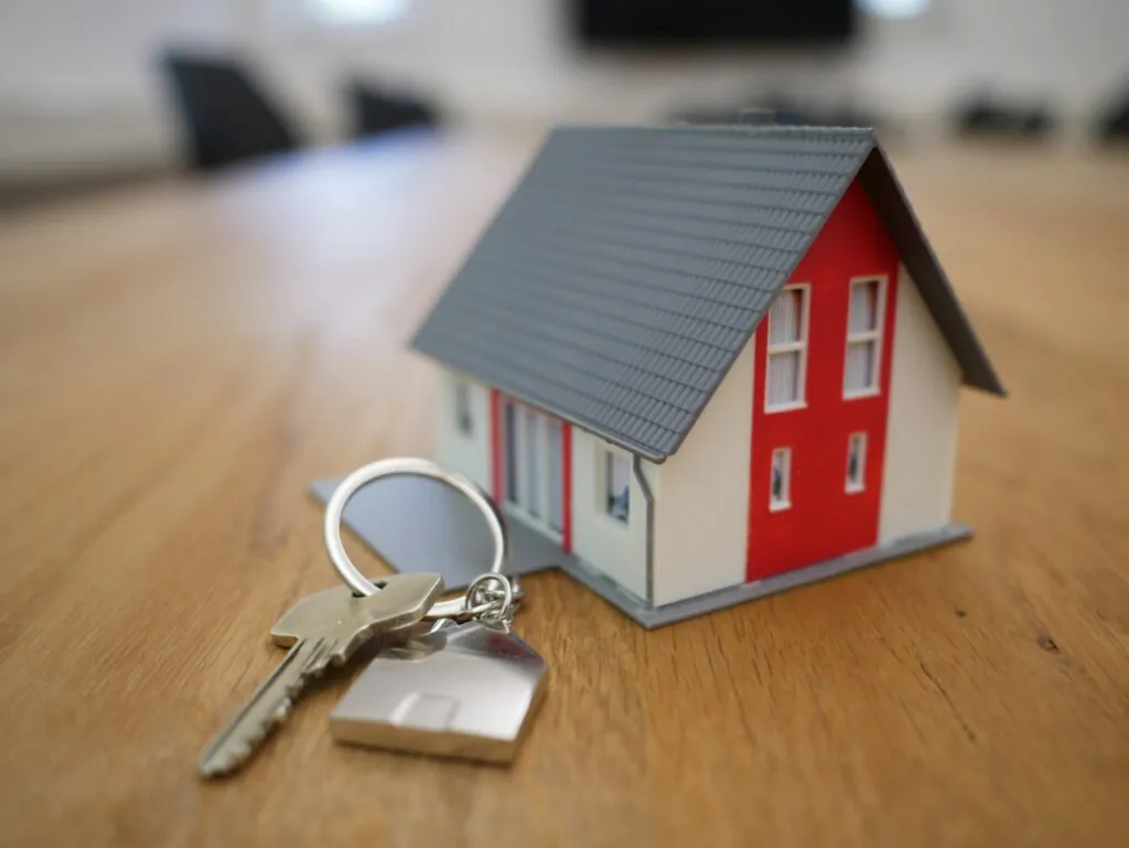 Keys and house model on table to represent house sale
